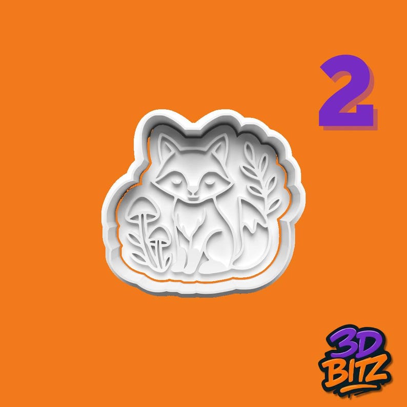 May include: A white plastic fox-shaped cookie cutter with a detailed design of a fox, mushrooms, and leaves. The cutter is on an orange background with the number 2 in purple and the 3D BITZ logo.