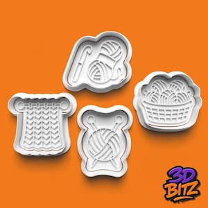 May include: Four white plastic cookie cutters in the shape of knitting and crochet tools. The shapes include a ball of yarn with a crochet hook, a basket of yarn balls, a knitted piece, and a ball of yarn with knitting needles. The background is orange.