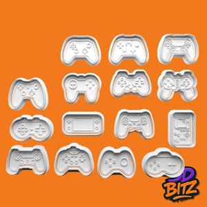 May include: A selection of white plastic cookie cutters shaped like video game controllers. The designs include different controller styles, featuring buttons and directional pads. The image is set against an orange background, with the "3D BITZ" logo in the bottom right corner.