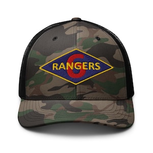 Könnte beinhalten: Eine schwarze und grüne Camouflage-Trucker-Kappe mit einem blauen und roten Diamanten-Patch, auf dem in gelben Buchstaben "6 RANGERS" steht.
