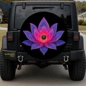 May include: Black spare tire cover featuring a vibrant, stylized lotus flower design. The flower has pink and purple petals with a bright center. The cover is mounted on a black Jeep. The text "SunshineSite Design" is visible.