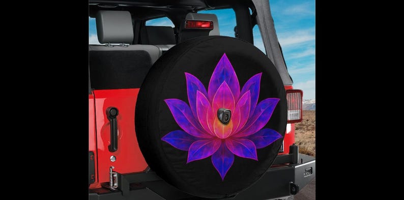 May include: Black spare tire cover featuring a vibrant lotus flower design in shades of purple, pink, and yellow. The cover is mounted on a red Jeep, with a glimpse of the interior and a scenic background.