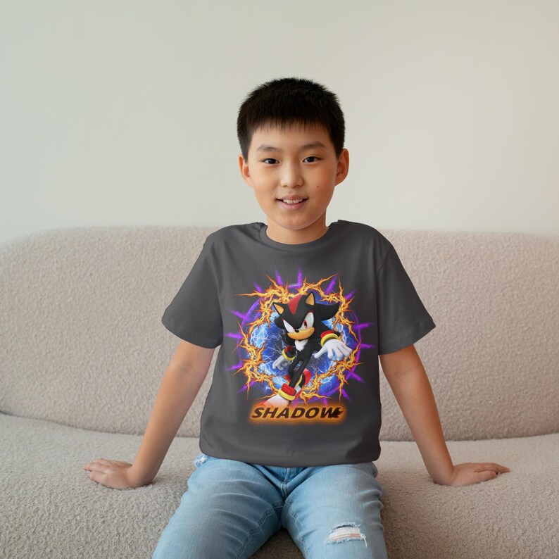 May include: A dark gray t-shirt with a graphic of Shadow the Hedgehog from the Sonic the Hedgehog video game series. The graphic features Shadow in a blue and orange energy field with the word "SHADOW" printed below.