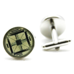 Peut inclure: Paire de boutons de manchette argentés. Chaque bouton de manchette présente un motif géométrique noir et gris sur fond vert clair. Les boutons de manchette sont présentés sur un fond blanc.