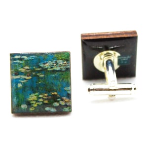 May include: A pair of cufflinks featuring a painting of water lilies. The cufflinks are made of wood and have a silver metal clasp.
