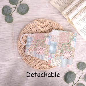 May include: A patchwork face mask with a floral design and a white elastic strap. The mask incorporates pink, blue, and white patterns, including floral prints and gingham checks. The word "Detachable" is printed in black.