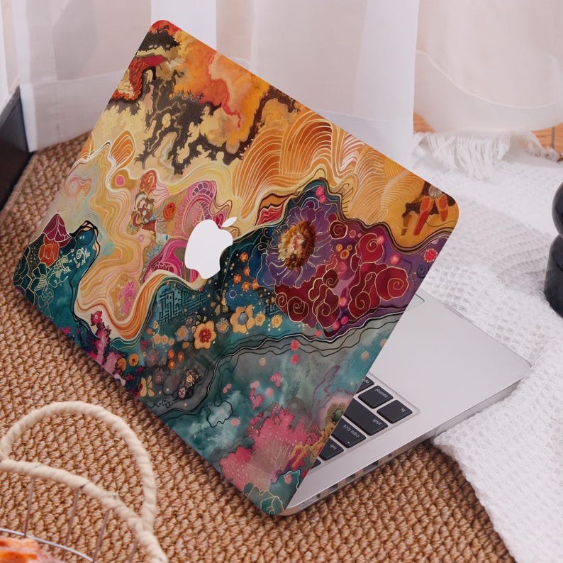 Op de afbeelding: Een laptop met een kleurrijk, abstract ontwerp. De hoes heeft een levendige mix van oranje, geel, blauwgroen en roze tinten, met bloem- en wolkenachtige patronen. Het Apple-logo is zichtbaar op het deksel van de laptop.