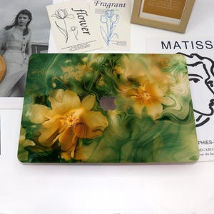 May include: A green and gold marble-like laptop skin with yellow flowers. The skin has a swirling pattern and a subtle gold glitter effect.