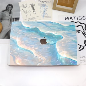 Puede incluir: Una funda para portátil con un diseño abstracto azul y blanco con un patrón de olas y detalles brillantes. La funda tiene un recorte para el logotipo de Apple.