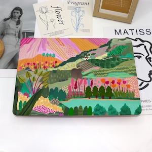 Può includere: Una pelle per laptop colorata con un design paesaggistico che presenta un lago, colline, alberi e fiori. Il design è dipinto in uno stile fantasioso con colori vivaci e linee audaci.