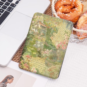 May include: A rectangular case featuring a vintage cottage scene with flowers and handwritten script. The case has a green, pink, and beige color palette. A laptop and a basket of baked goods are in the background.