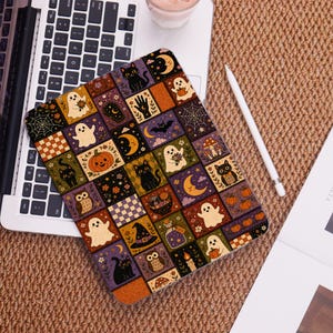 Könnte beinhalten: Eine rechteckige Tablethülle mit einem sich wiederholenden Gittermuster aus Halloween-Illustrationen, darunter schwarze Katzen, weiße Geister, orangefarbene Kürbisse, Mondsicheln, Eulen, Hexenhüte, Zaubertrankflaschen und Spinnennetze in dunklen Farben.