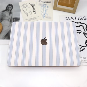 May include: A white laptop case with blue stripes and an apple logo. The case has a striped design.