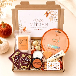 May include: A gift box containing bath salts, a round face mask packet labelled Hydrate Hyaluronic Acid, two Pukka vanilla chai tea bags, a heart-shaped soap, a vanilla lip balm, a pumpkin spiced latte candle, and a box of matches with autumn art.