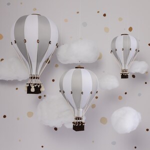 May include: Three white and gray striped hot air balloons with brown baskets hanging from white fluffy clouds against a light gray background with brown and beige confetti.