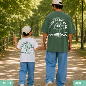 May include: A white t-shirt with "GOLF DAD'S CADDIE" text and a golf ball graphic, and a moss green t-shirt with "GOLF DADS CLUB" text and a golf ball graphic. Both shirts have the text "EST 2026" and are worn by a parent and child.