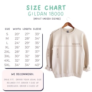 May include: A beige crewneck sweatshirt displayed on a hanger with a size chart for Gildan 18000 adult unisex sizing. The chart lists width, length, and sleeve measurements in inches from sizes S to 5XL, with recommendations for fit.