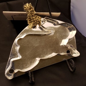 May include: A silver metal cookie cutter shaped like a bunny rabbit. The cutter has a hole in the bottom for hanging.