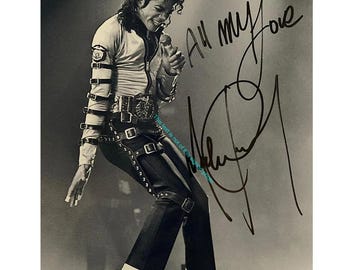 May include: A black and white photograph of a performer in a light-coloured jacket with multiple buckled straps on the sleeves, dark trousers, white socks, and black shoes. The image features a handwritten signature and the text All my love.