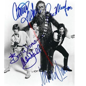 May include: A black and white photo of four Star Wars characters, including Han Solo, Luke Skywalker, Princess Leia, and Chewbacca. The photo is signed by all four actors. The signatures are in blue ink.