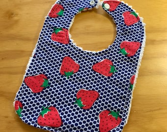 May include: A blue and white baby bib with a white trim and a strawberry pattern.