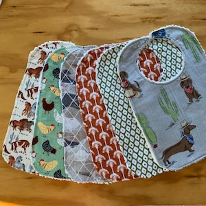 May include: A set of eight baby bibs with different patterns. The bibs are made of soft, absorbent fabric and have a unique design. The patterns include a variety of animals, plants, and geometric shapes. The bibs are perfect for keeping baby's clothes clean during mealtime.