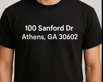 May include: Black crew neck t-shirt with white text: "100 Sanford Dr Athens, GA 30602". The shirt is made of a soft material and has short sleeves. The text is centered on the front of the shirt.