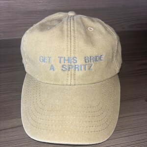 Funny wedding weekend bride hat on neutral background, personalised hen party cap with orange embroidery