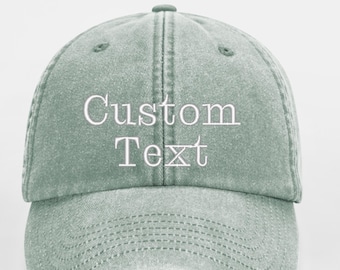 May include: A light green, distressed, cotton baseball cap with white embroidered text that reads "Custom Text".