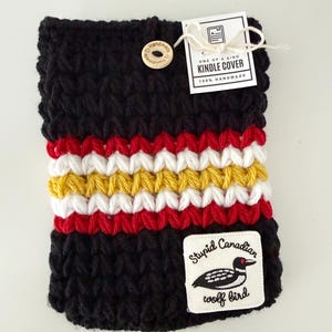 Pode incluir: Capa Kindle preta feita à mão com listras vermelhas, brancas e amarelas. Possui um fecho de botão de madeira e um patch que diz "Stupid Canadian wolf bird" com uma ilustração de um mergulhão. Inclui uma etiqueta que diz "ONE OF A KIND KINDLE COVER 100% HANDMADE".