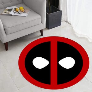 May include: A round red and black rug with a white Deadpool logo. The logo features a red outline and two white eyes.