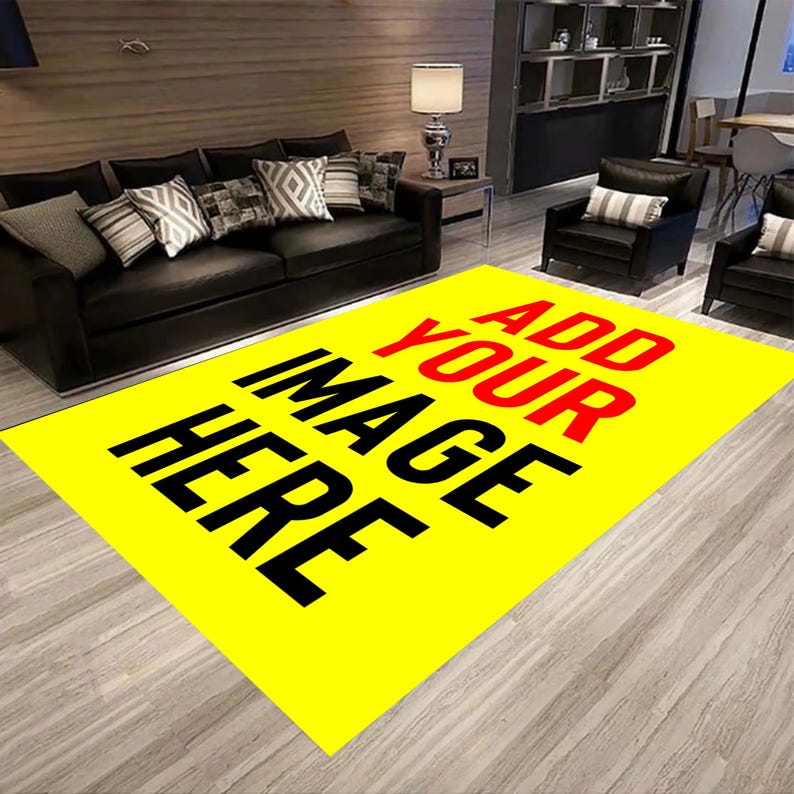May include: A large, rectangular yellow rug with the text "ADD YOUR IMAGE HERE" in black and red. The rug is in a living room setting with a black sofa, armchairs, and decorative pillows. The rug is placed on a light-colored wooden floor.