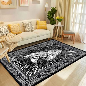 May include: Black and white area rug featuring a detailed illustration of a spaceship with a burst design. The rug has a decorative border and is placed in a living room setting with a sofa and pillows.