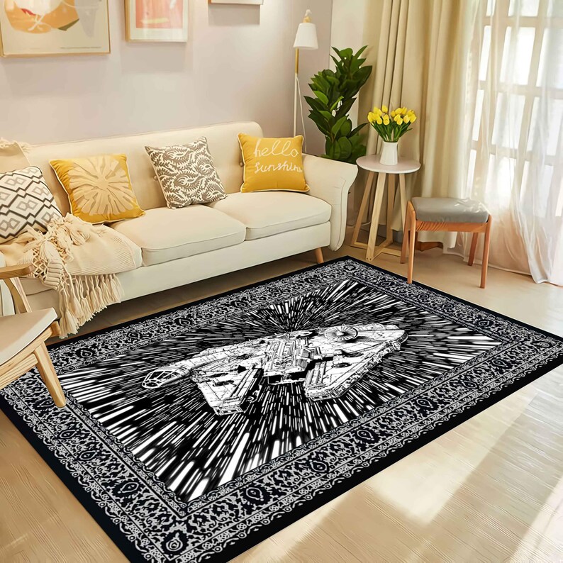 May include: Black and white area rug featuring a detailed illustration of a spaceship with a burst design. The rug has a decorative border and is placed in a living room setting with a sofa and pillows.
