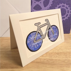 Carte d'art bicyclette avec cadre dessiné à la main et roues galaxie aquarelle