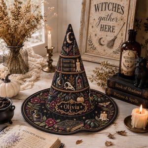 May include: A black conical hat featuring a quilted texture and intricate illustrations of moons, bats, potions, books, and pumpkins. The name Olivia is printed in gold lettering on the front, surrounded by floral patterns and a book graphic.