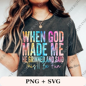 May include: Dark gray t-shirt with the text "WHEN GOD MADE ME HE GRINNED AND SAID 'This'll Be Fun'" in colorful tie-dye lettering. The shirt also has the text "PNG + SVG" at the bottom.