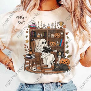 Könnte beinhalten: Cremefarbenes T-Shirt mit einer Halloween-Illustration. Es zeigt einen Geist, der in einem Stuhl liest, mit einem Bücherregal, Kürbissen, Kerzen und einer schwarzen Katze. Der Text "PNG + SVG" ist ebenfalls sichtbar.