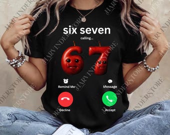 May include: Black t-shirt featuring the text "six seven calling...". The design shows the numbers 6 and 7 as red fruits with faces, and phone interface icons for decline and accept.