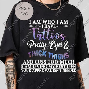 May include: Black t-shirt with the text "I AM WHO I AM I HAVE Tattoos Pretty Eyes & THICK THIGHS AND CUSS TOO MUCH I AM LIVING MY BEST LIFE YOUR APPROVAL ISN'T NEEDED". The text is in white, purple, and blue.