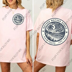 A woman wearing a pink t-shirt with a graphic design on the back.