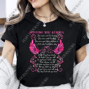 May include: Black t-shirt with the text "MISSING YOU ALWAYS" in pink script. The design includes pink angel wings and a heart, with a poem about loss. A heartfelt memorial tee.