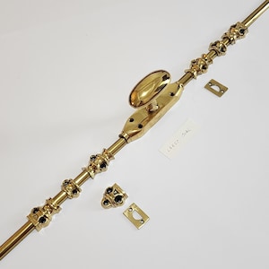 Könnte beinhalten: Ein Fensterriegel aus Messing mit ovalem Griff und dekorativen schwarzen Akzenten. Inklusive passendem Schließblech und Halterung. Der Text "LARGE OVAL" befindet sich auf einem kleinen weißen Etikett. Ideal für die Restaurierung antiker Fenster.