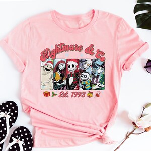 Puede incluir: Camiseta rosa con un gr&aacute;fico de personajes de la pel&iacute;cula "Pesadilla antes de Navidad" y el texto "Nightmare & Co. Est. 1993".