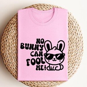K&ouml;nnte beinhalten: Pinkes T-Shirt mit einer schwarzen Grafik eines Kaninchens mit Sonnenbrille und dem Text "No bunny can fool me!"