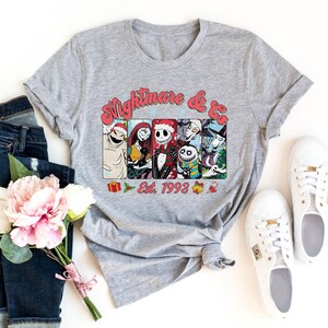Puede incluir: Camiseta gris con un gr&aacute;fico de Pesadilla Antes de Navidad con Jack Skellington y otros personajes. El texto "Nightmare & Co. Est. 1993" est&aacute; impreso en la camiseta.