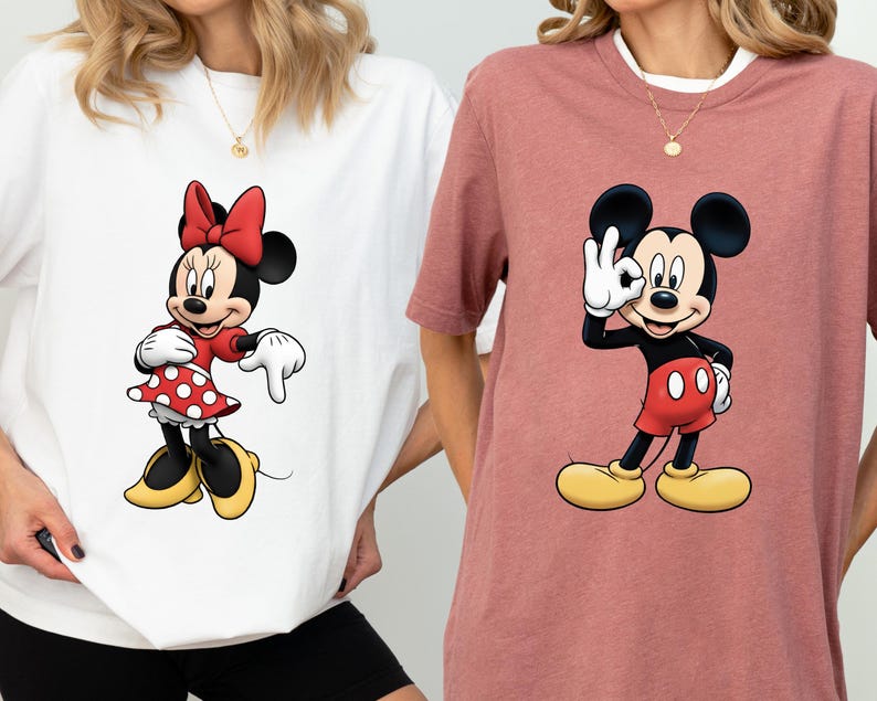 May include: Two t-shirts featuring cartoon characters. One is white with Minnie Mouse in a red dress with white polka dots and a red bow. The other is a mauve shirt with Mickey Mouse giving an "okay" hand gesture.
