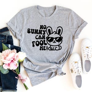 K&ouml;nnte beinhalten: Ein graues T-Shirt mit einer schwarzen Grafik eines Kaninchens mit Sonnenbrille und dem Text "No bunny can fool me!"