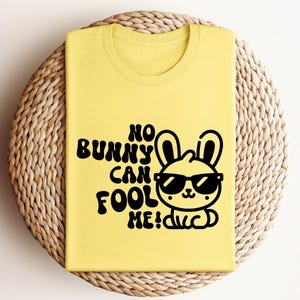 K&ouml;nnte beinhalten: Gelbes T-Shirt mit einem schwarzen Motiv eines Kaninchens mit Sonnenbrille und dem Text "No bunny can fool me!"