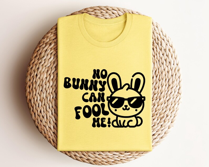 K&ouml;nnte beinhalten: Gelbes T-Shirt mit einem schwarzen Motiv eines Kaninchens mit Sonnenbrille und dem Text "No bunny can fool me!"